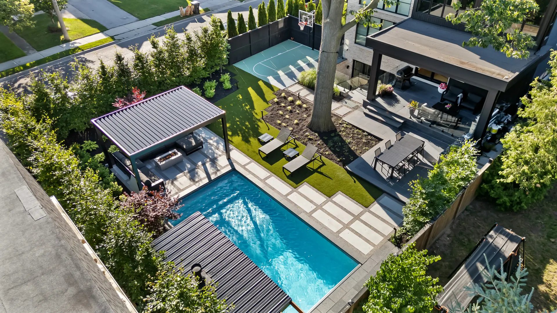 Modern backyard with pool, lounge chairs, and landscape lighting at dusk in the GTA