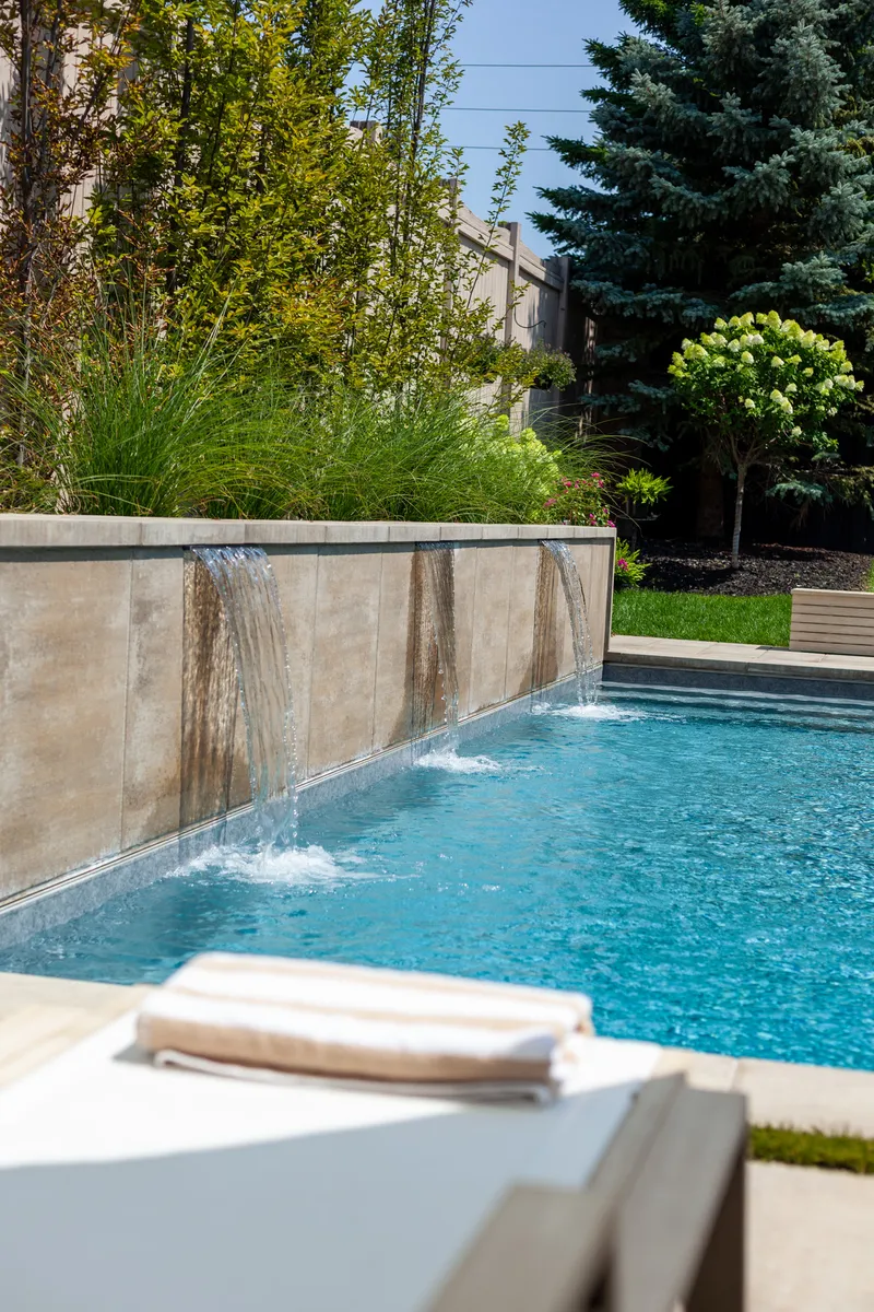 Poolside water feature with cascading water in an Ontario backyard