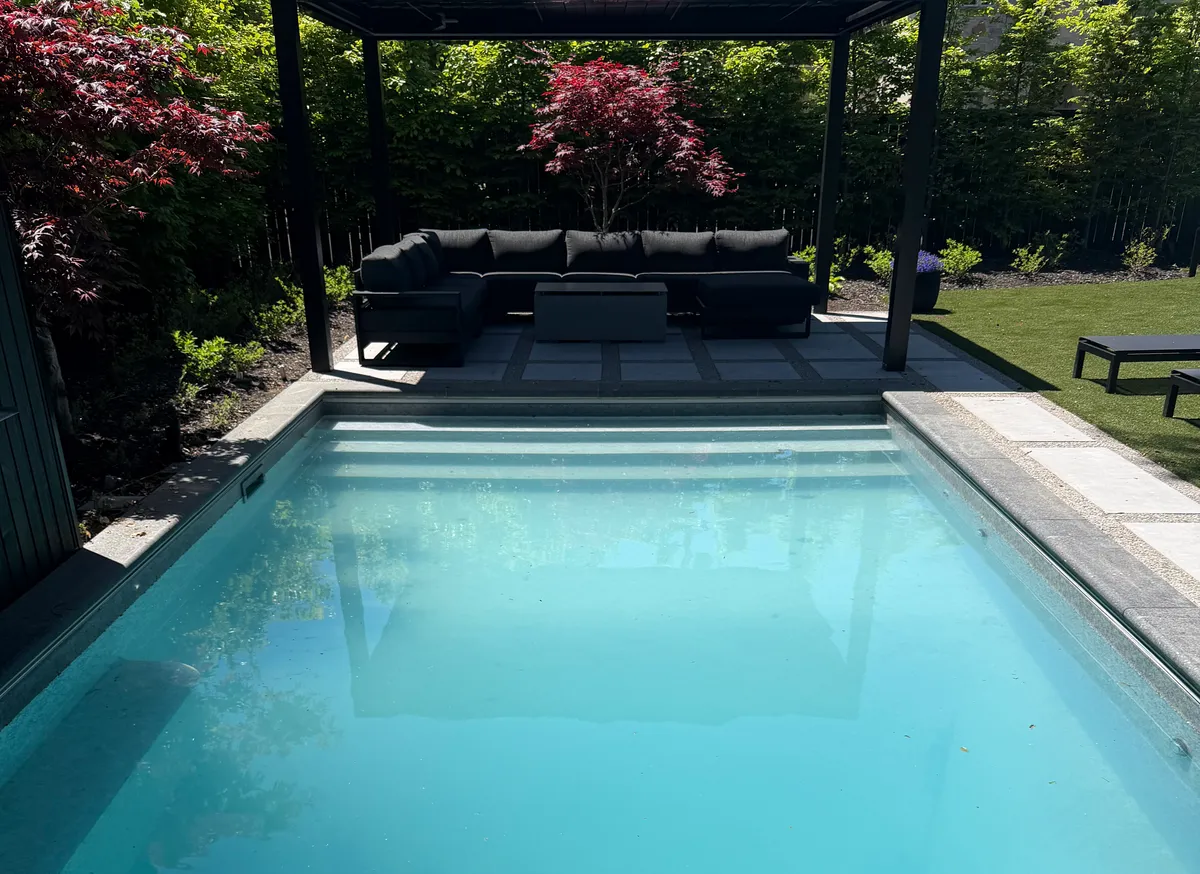 Backyard pool with pergola-covered lounge seating in a landscaped Ontario backyard