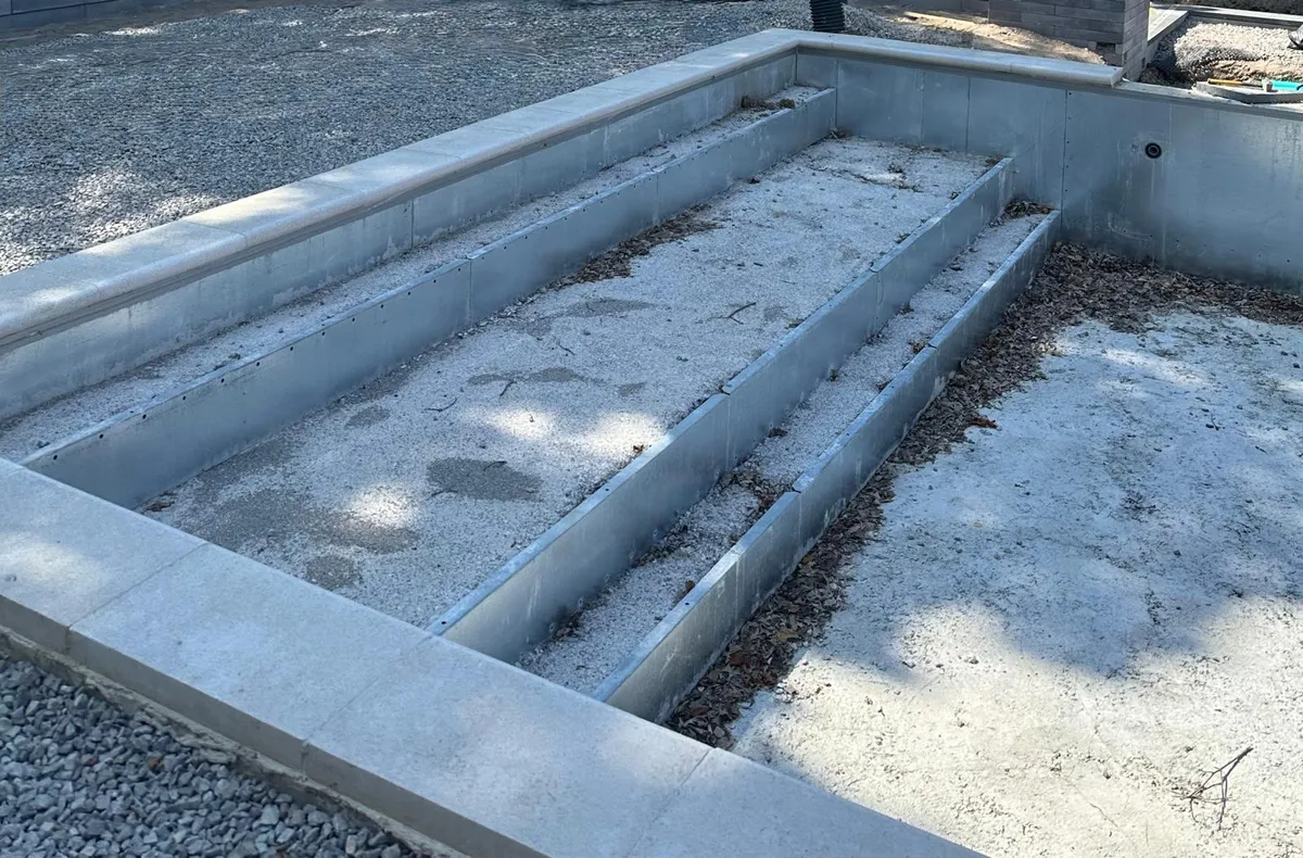 Empty concrete pool shell with steps prepared for restoration work