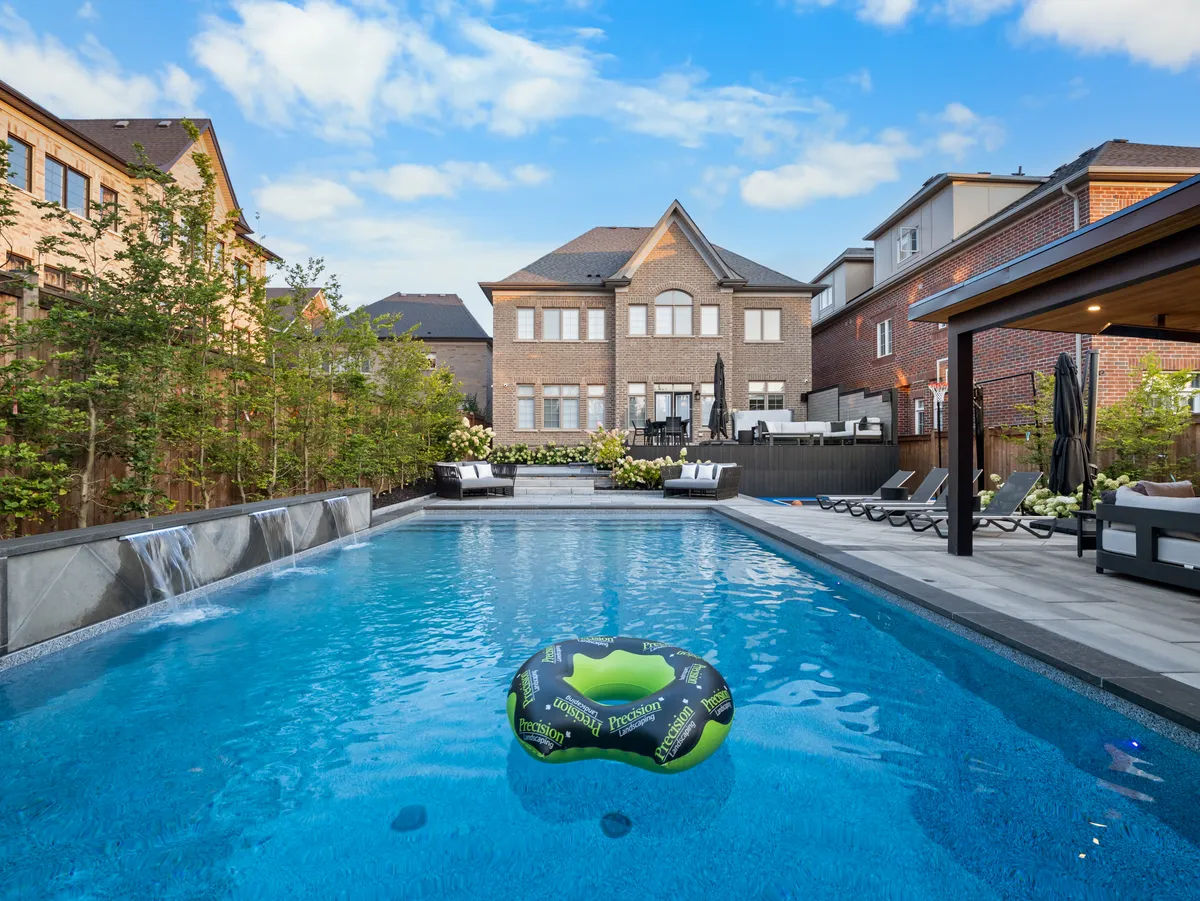 Backyard pool with waterfall feature, lounge seating, and landscaping in Ontario