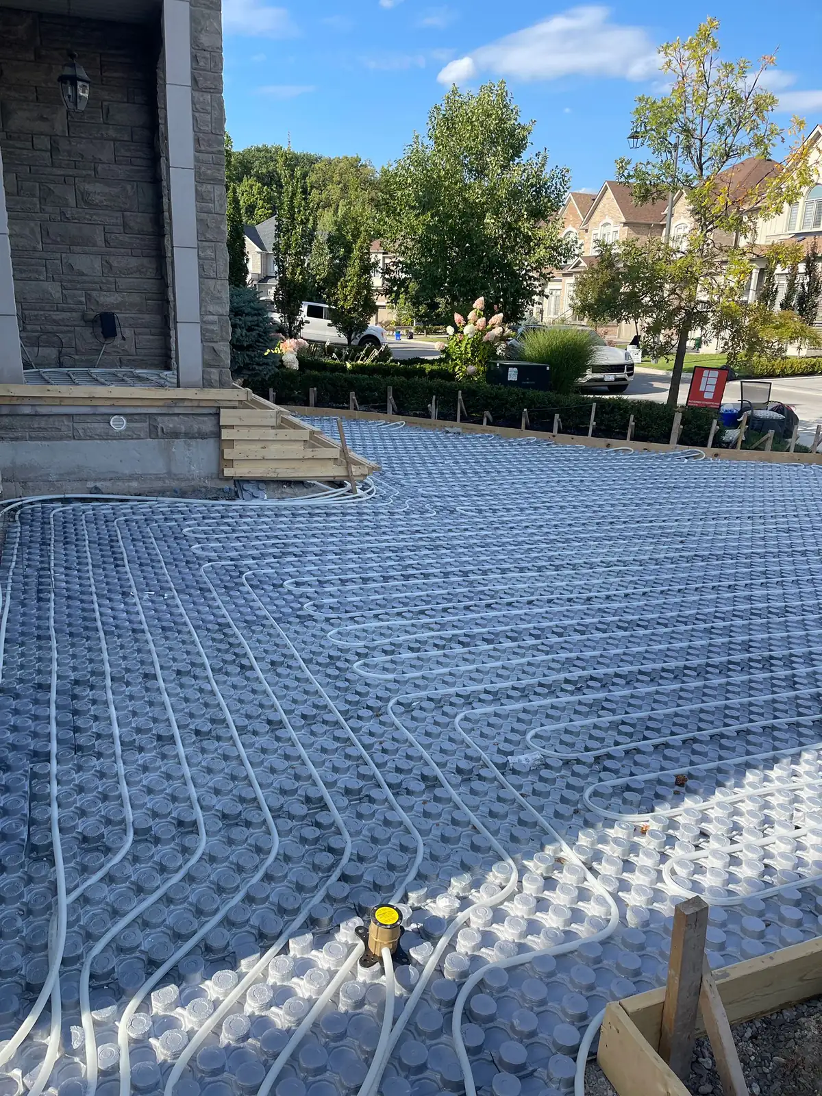 Hydronic snowmelt tubing laid across insulated panels on a driveway before the surface is poured