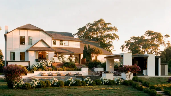 Brule landscape design render &mdash; The house and cabana seen across the lawn at golden hour, hydrangea borders below the pool terrace