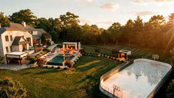Brule landscape design render &mdash; Aerial view at sunset — infinity-edge pool, custom cabana and the private hockey rink against the tree line