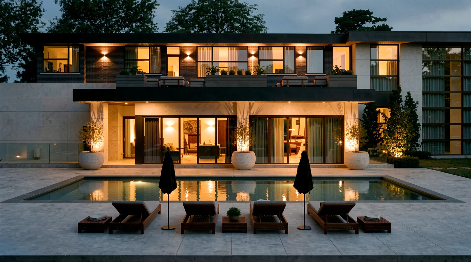 Waymar residence at night &mdash; tanning ledge pool with loungers and lit umbrellas in front of the home