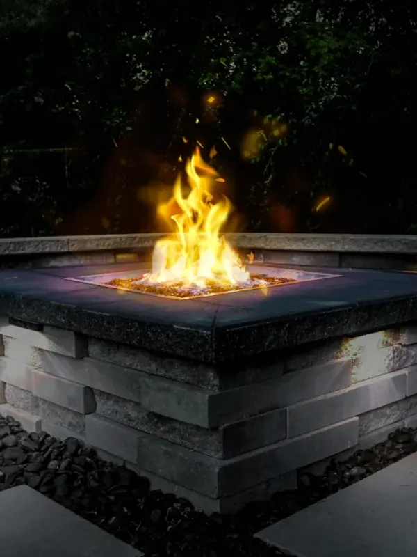 Square stone fire pit burning at dusk