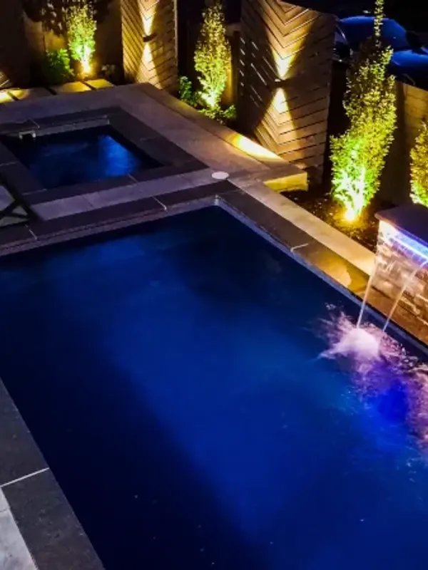 Inground pool and hot tub lit at night